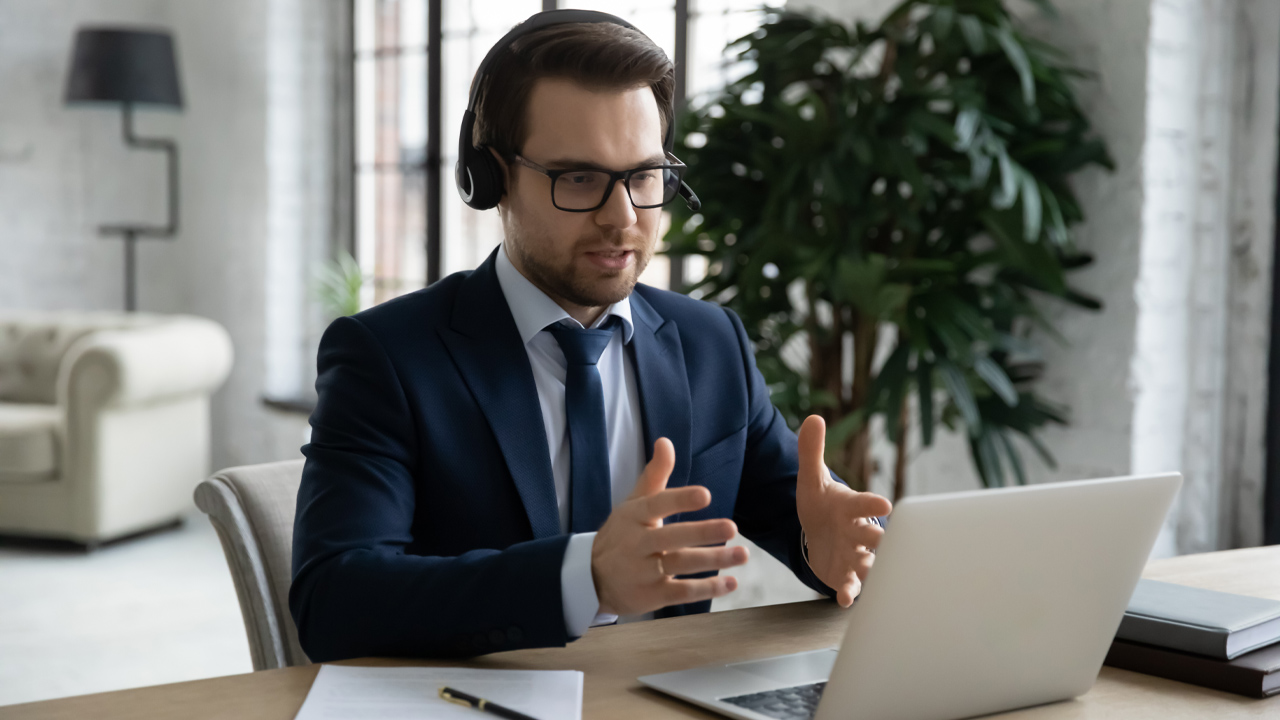 Man med headset som pratar med någon via datorn