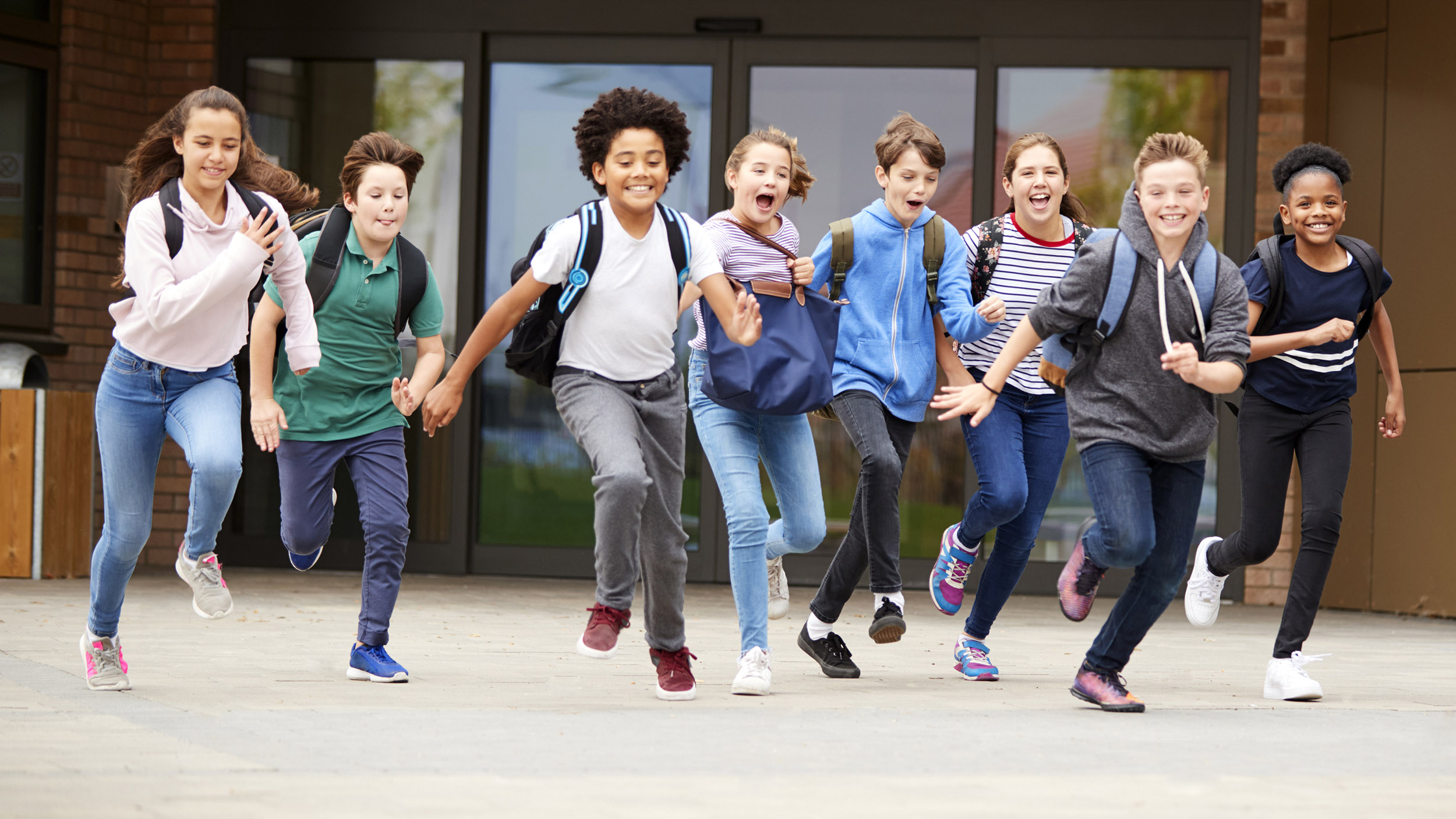En gjeng med barn som løper ut fra skolen