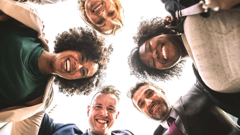 Coworkers standing in a ring and smiling